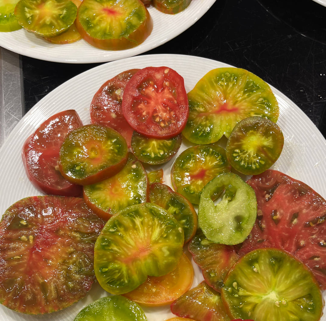 Aufgeschnittene Tomaten verschiedener Sorten und Farben auf weissen Tellern